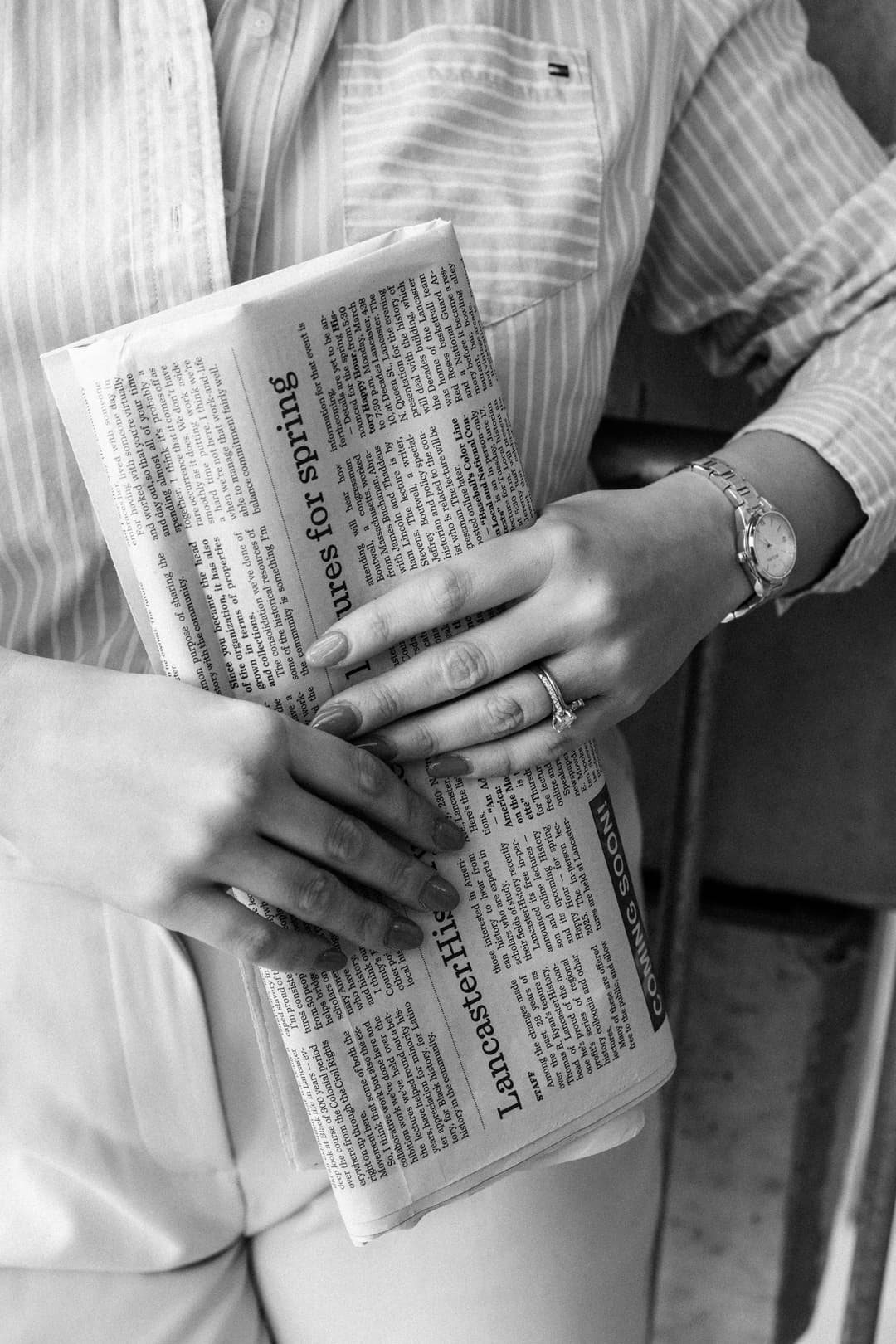 Black and white detail shot of hands holding vintage newspaper