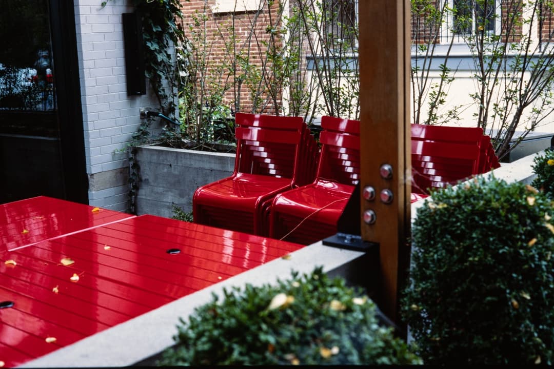 Modern outdoor seating area with red chairs and greenery