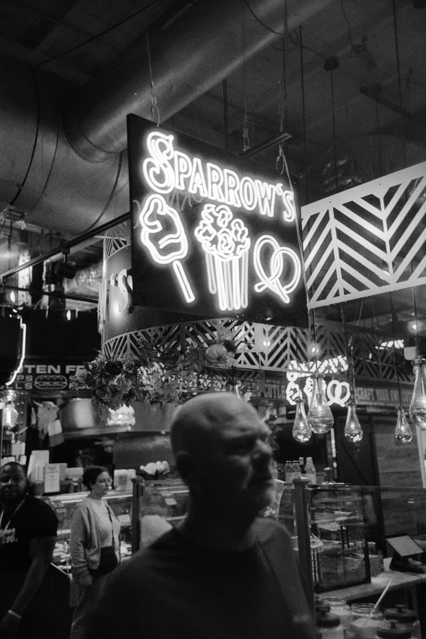 Black and white photo of a vintage store interior with neon signs, retro shopping scene