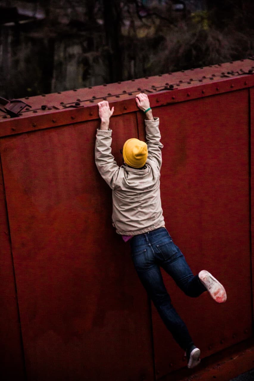 Person hanging from a red train car, urban exploration photography