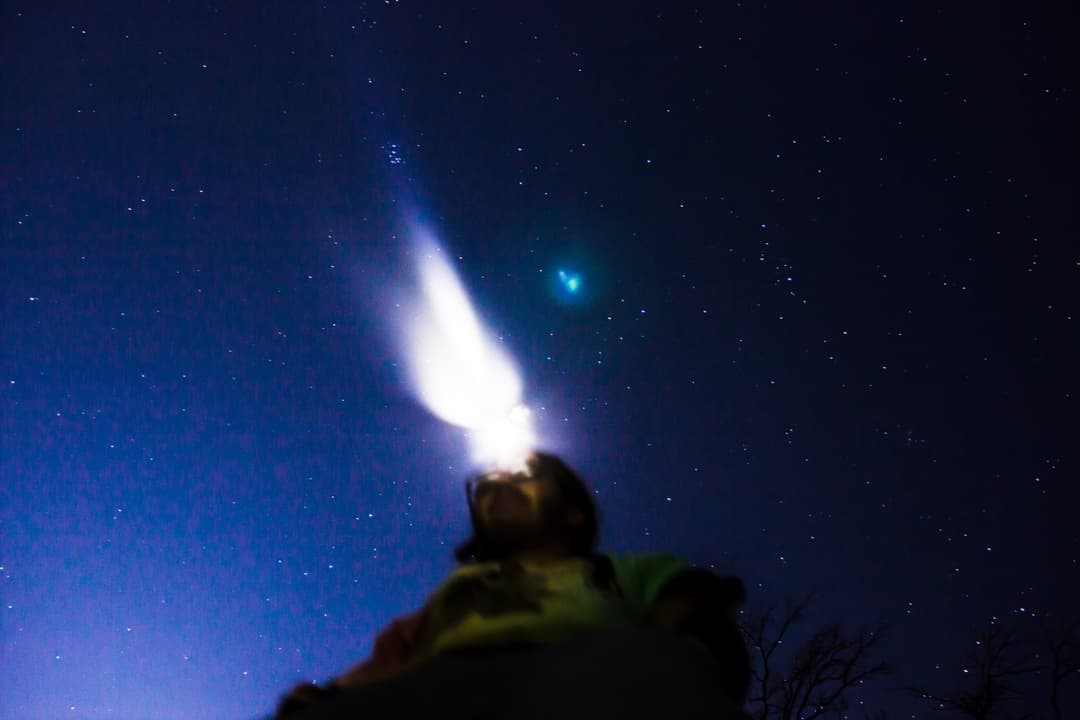 Person looking at the night sky with a bright star, stargazing adventure