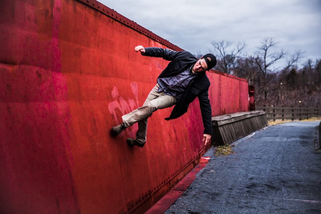 Skateboarder performing a trick on a red wall, urban skateboarding photography