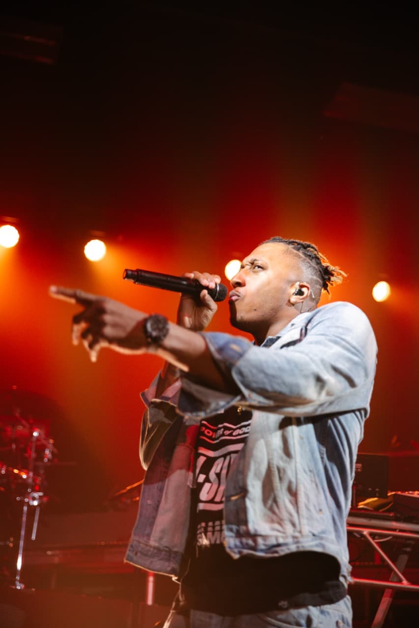 Energetic hip-hop concert: Rapper performing live on stage with microphone and denim jacket