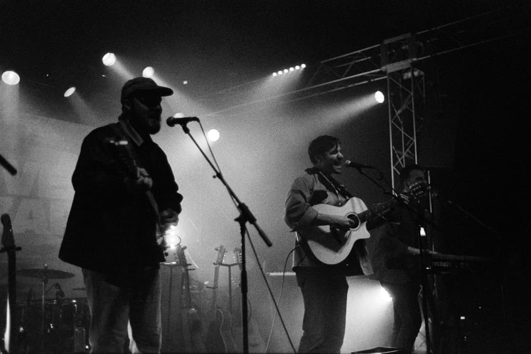 Black and white concert photography: Band performing on stage with microphones and stage lighting