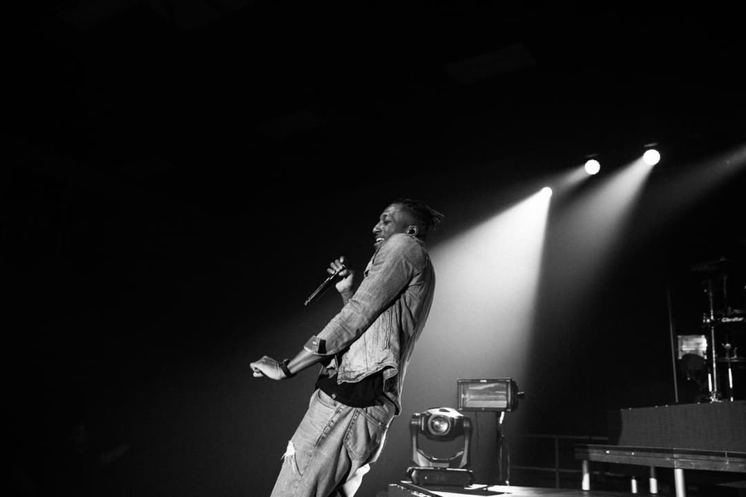 Black and white concert photography: Singer-songwriter performing with guitar under spotlight at live show