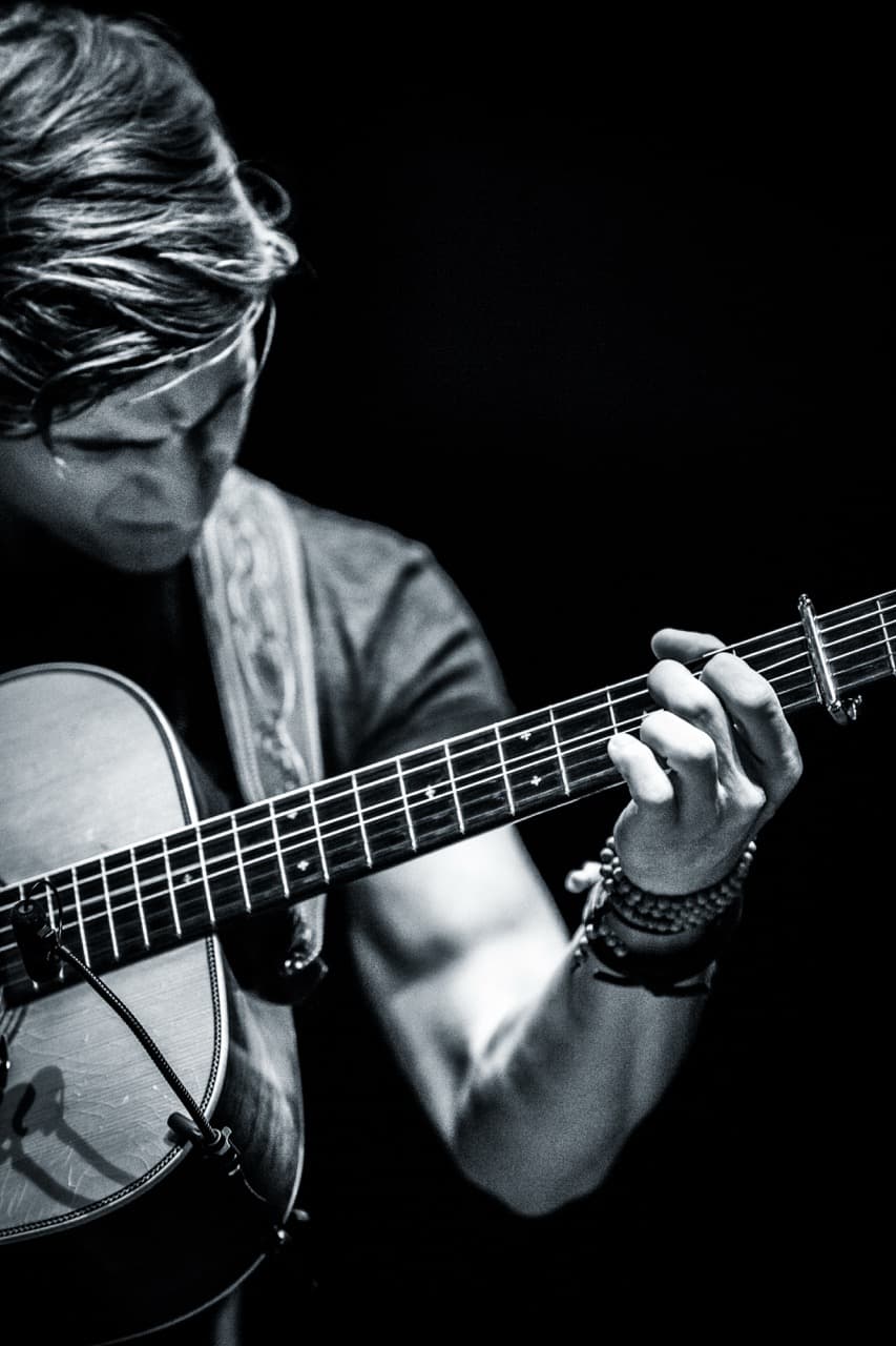 Black and white guitar photography: Close-up of musician playing acoustic guitar at concert