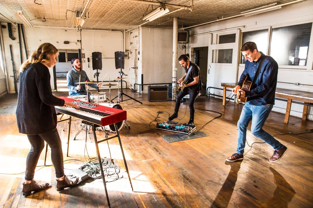 Band rehearsal: Musicians practicing in studio with keyboard, guitar, and bass in sunlit room