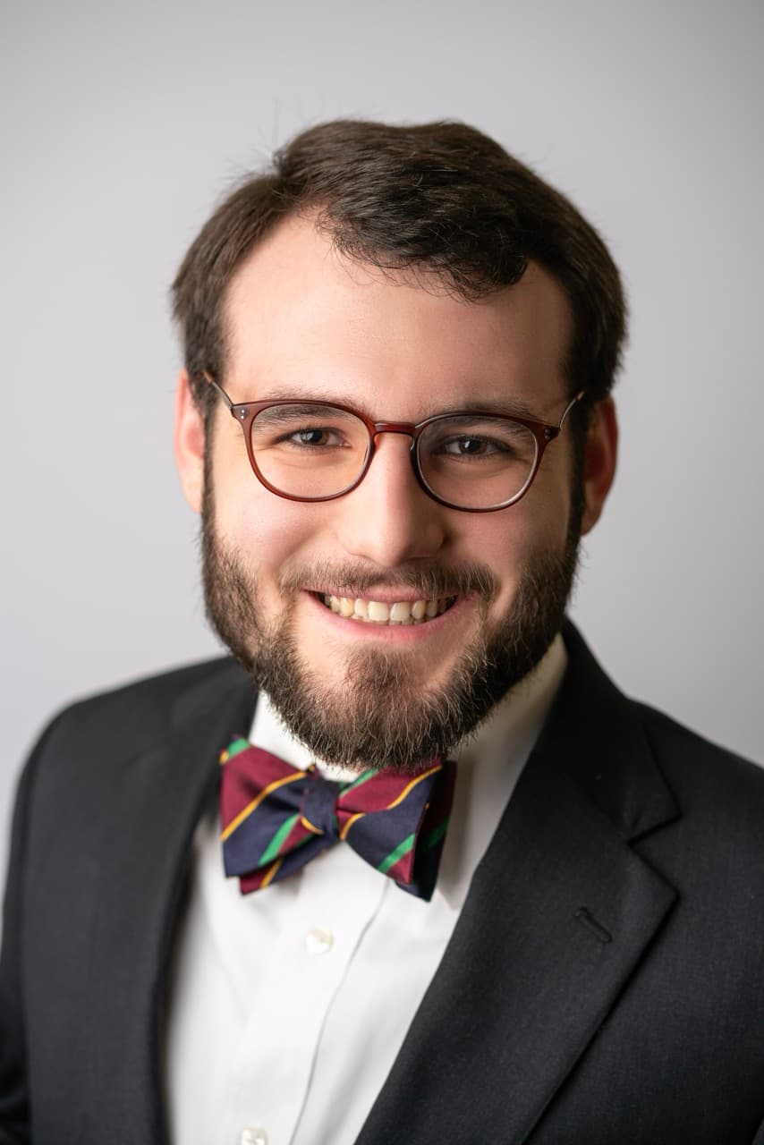 Professional headshot: Man with glasses and bow tie in formal attire