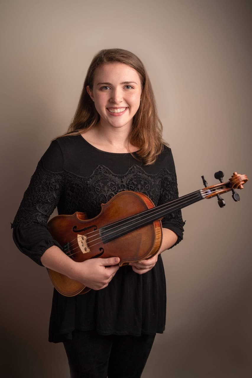 Musician portrait: Woman holding violin in studio setting with soft lighting