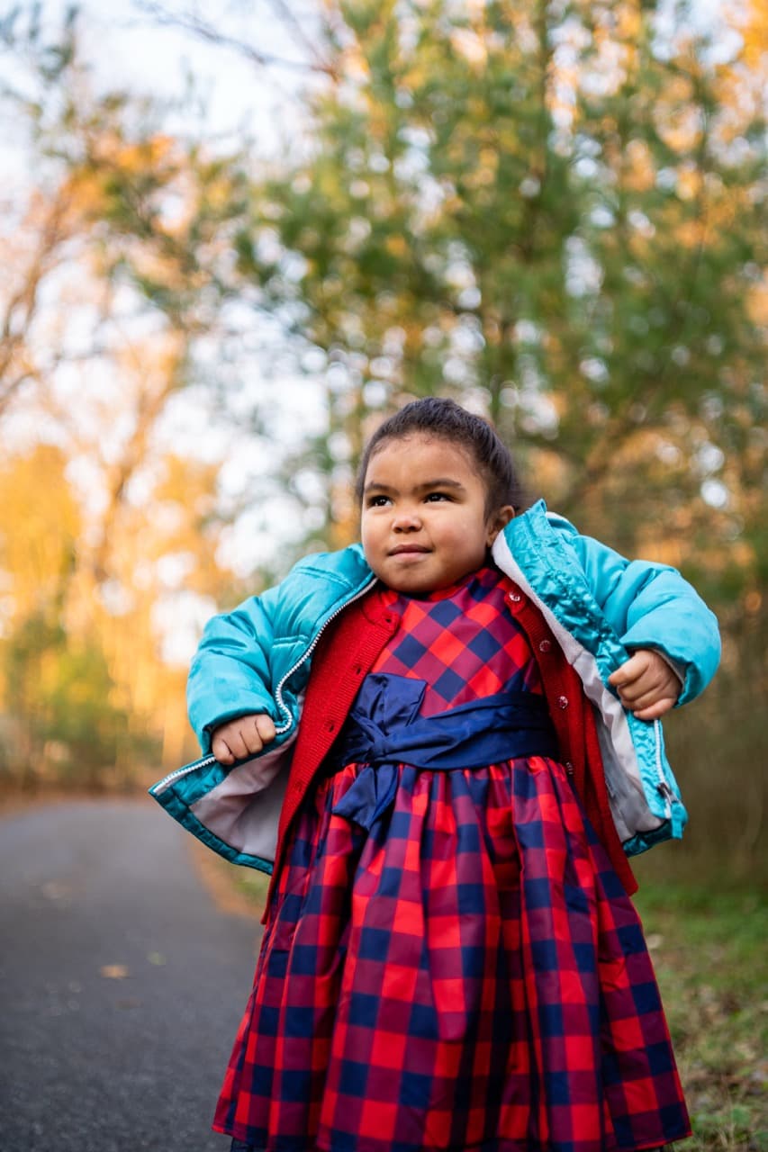 Child portrait: Young girl in colorful outfit in outdoor setting with autumn foliage