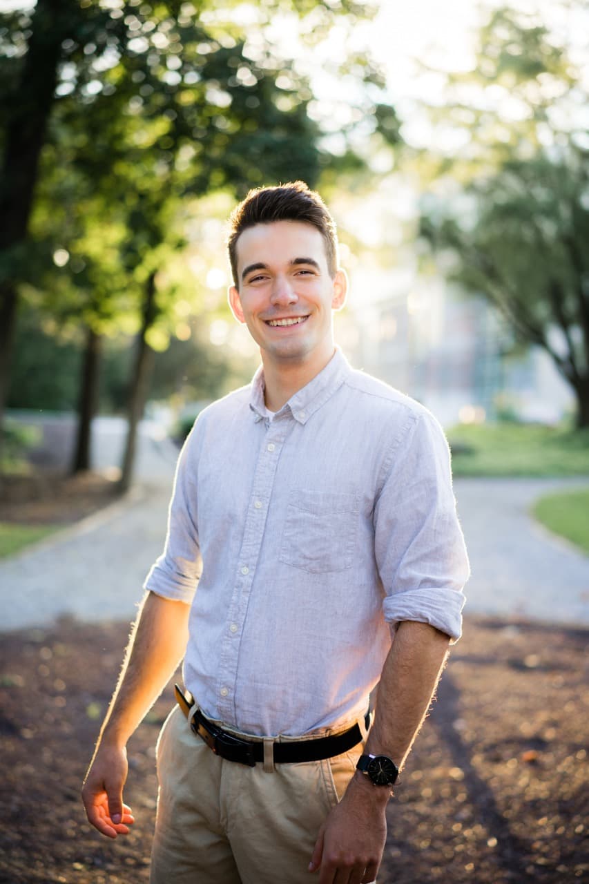 Outdoor portrait: Man smiling in park with natural lighting and greenery