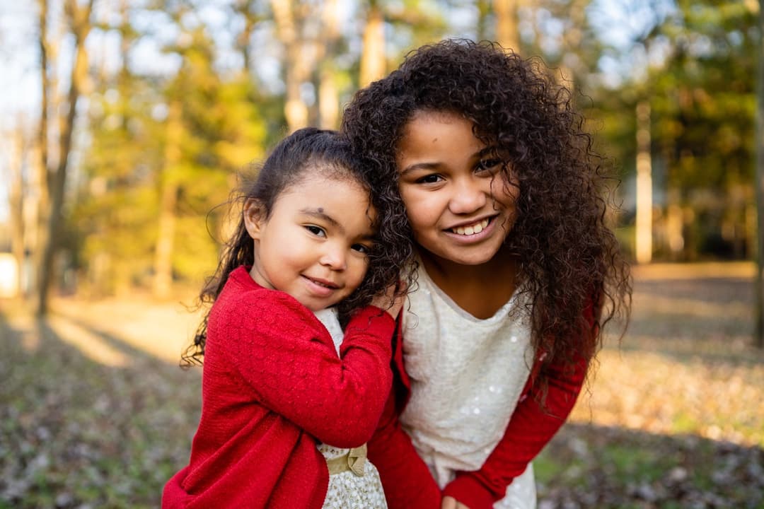 Children's portrait: Two young girls smiling and embracing in outdoor setting