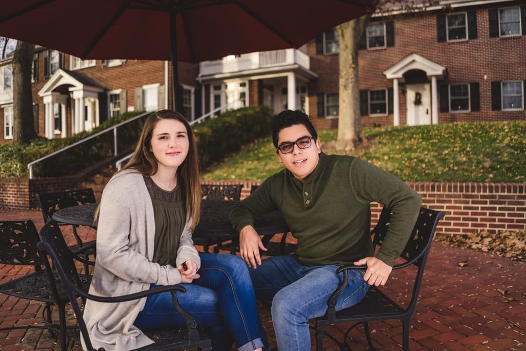 Couple portrait: Couple sitting on bench in outdoor setting with brick building background