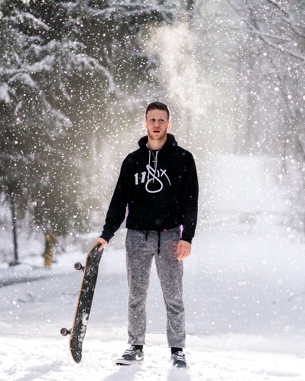 Winter portrait: Young man holding skateboard in snowy outdoor setting