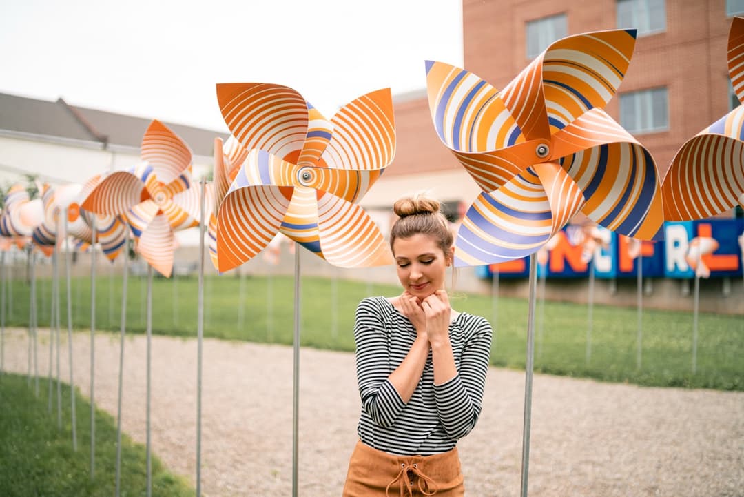 Lifestyle portrait: Woman standing in front of windmills in outdoor setting