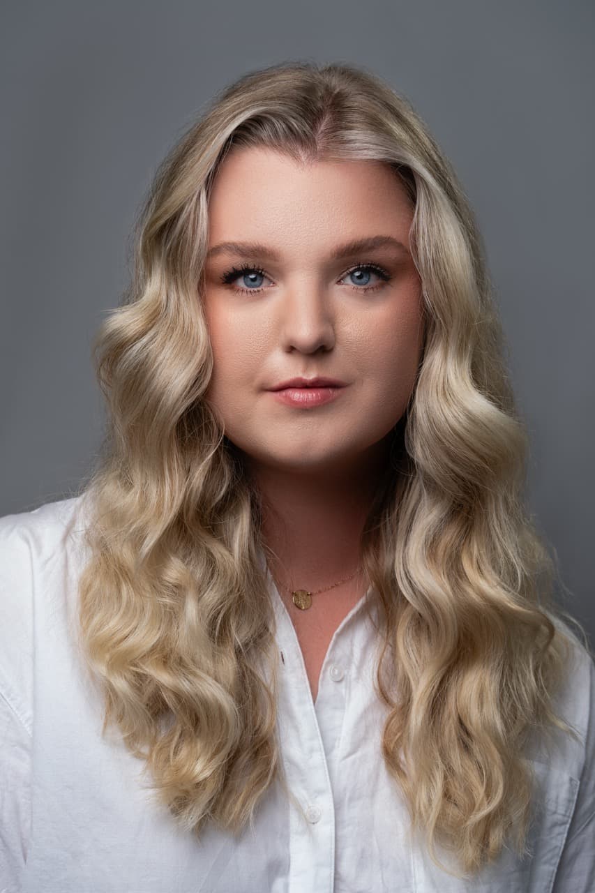 Professional headshot: Woman with blonde hair in studio setting with neutral background