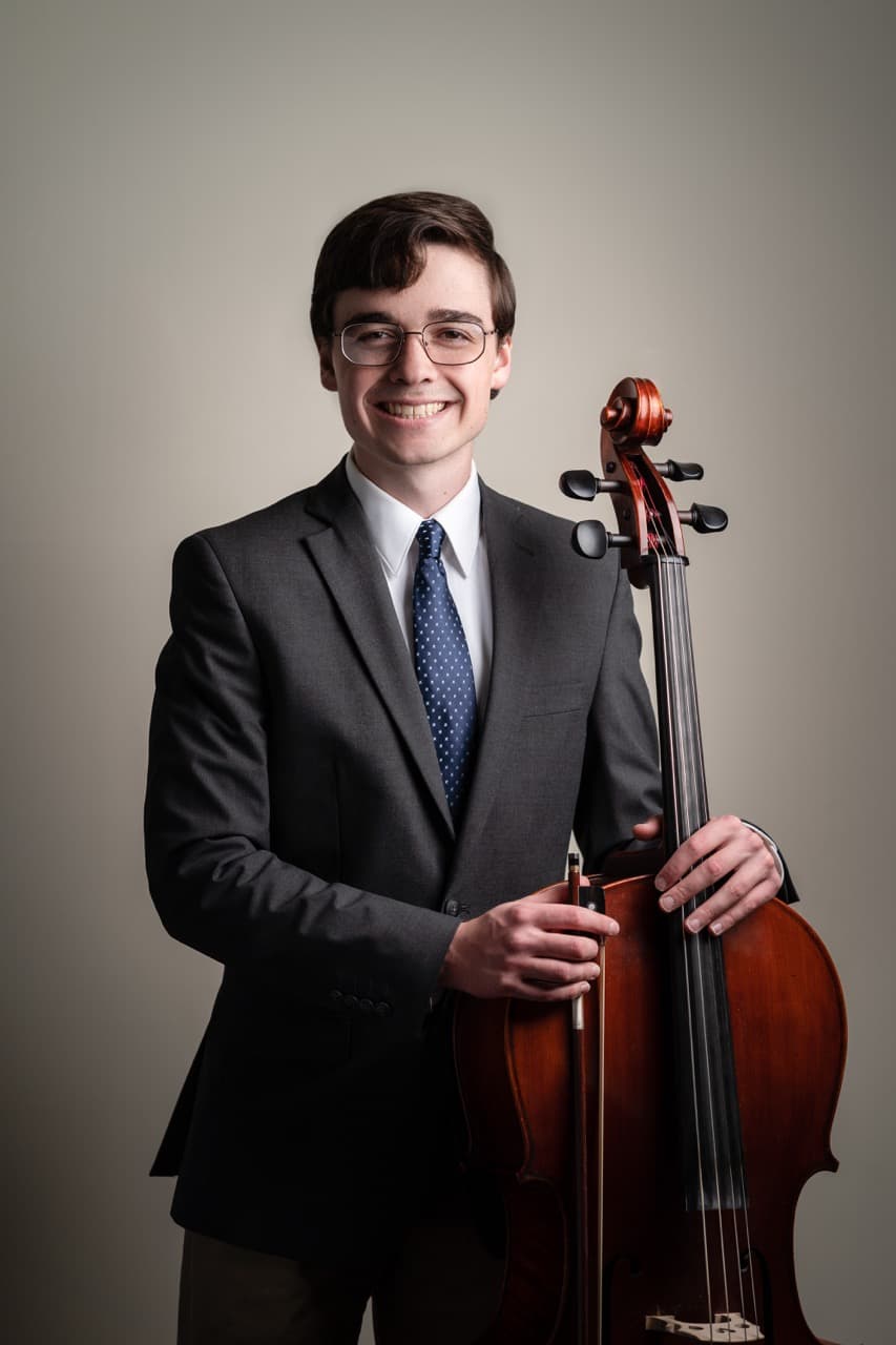 Musician portrait: Young man with cello in formal attire and professional setting