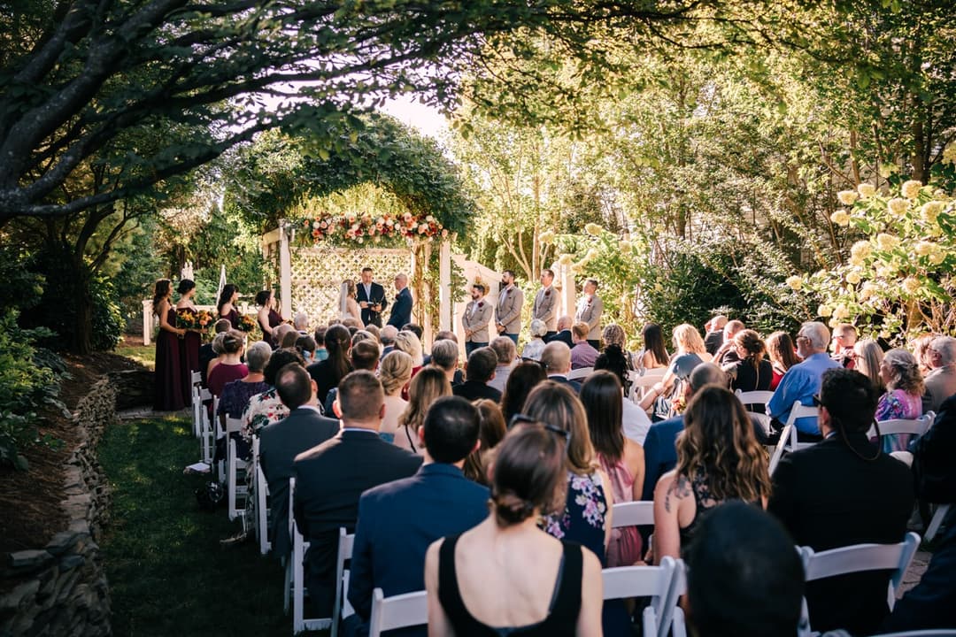 Outdoor wedding ceremony with guests seated under trees, garden wedding