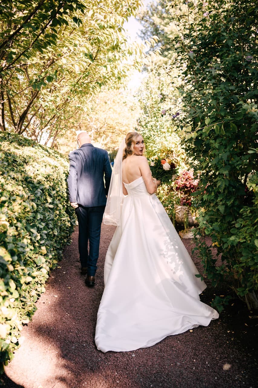 Bride and groom walking through a green tunnel, outdoor wedding portrait