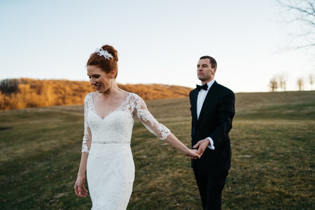 Bride and groom holding hands in a field, outdoor wedding portrait