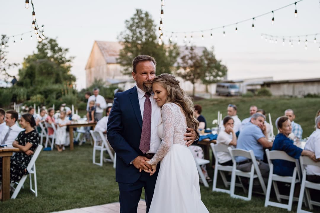 Bride and groom embracing at an outdoor wedding reception, sunset wedding photo