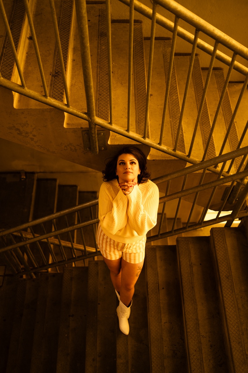 Model posed against dark stairwell with dramatic lighting