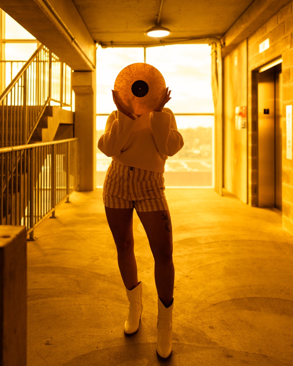 Model holding vintage camera in sunlit industrial hallway