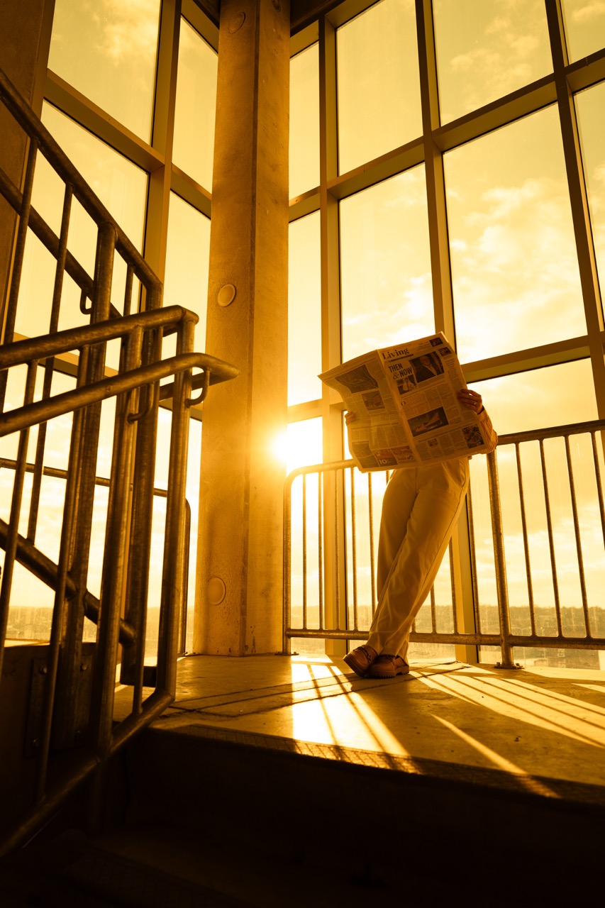 Model reading newspaper with dramatic window backlighting