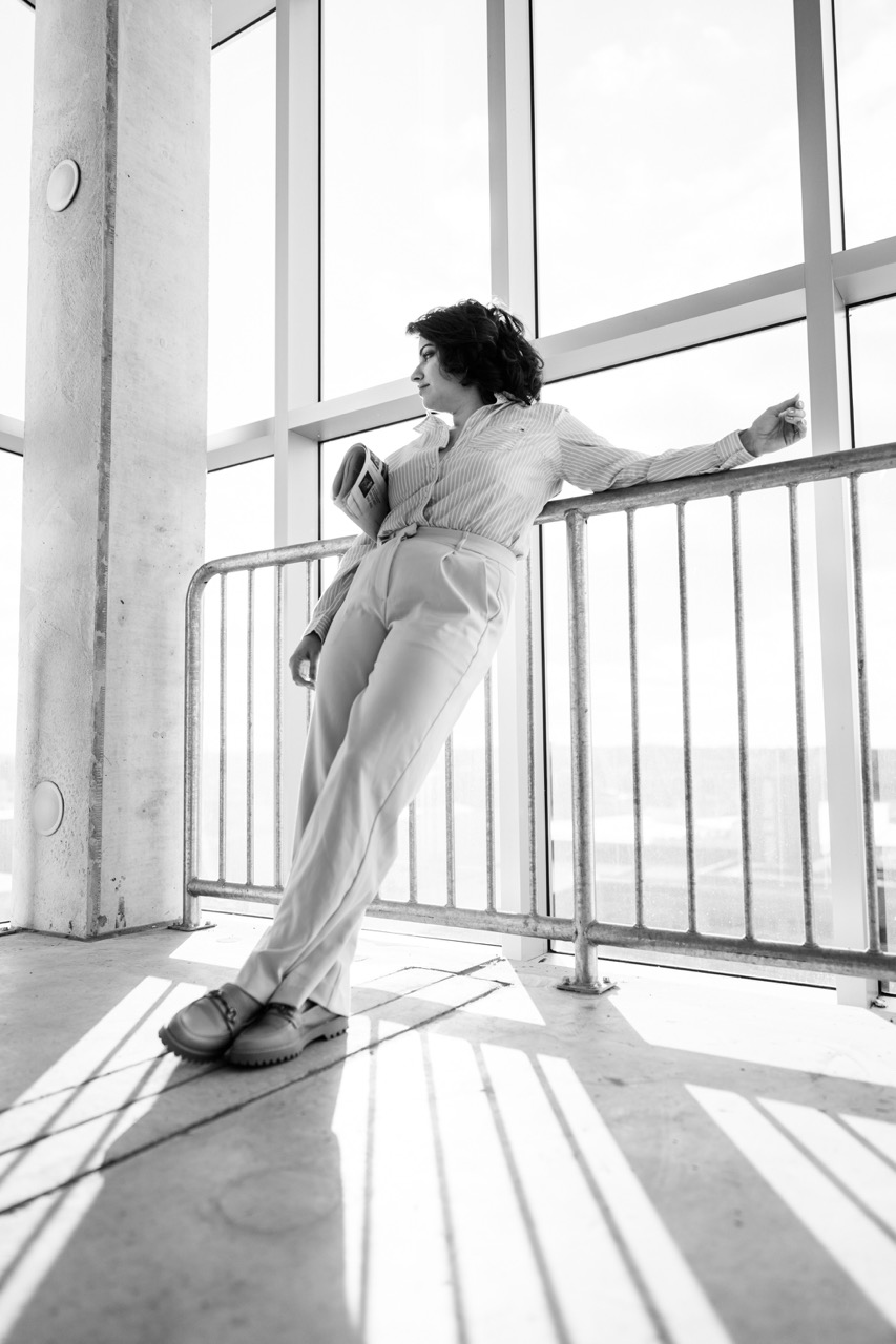 Model leaning against railing in black and white