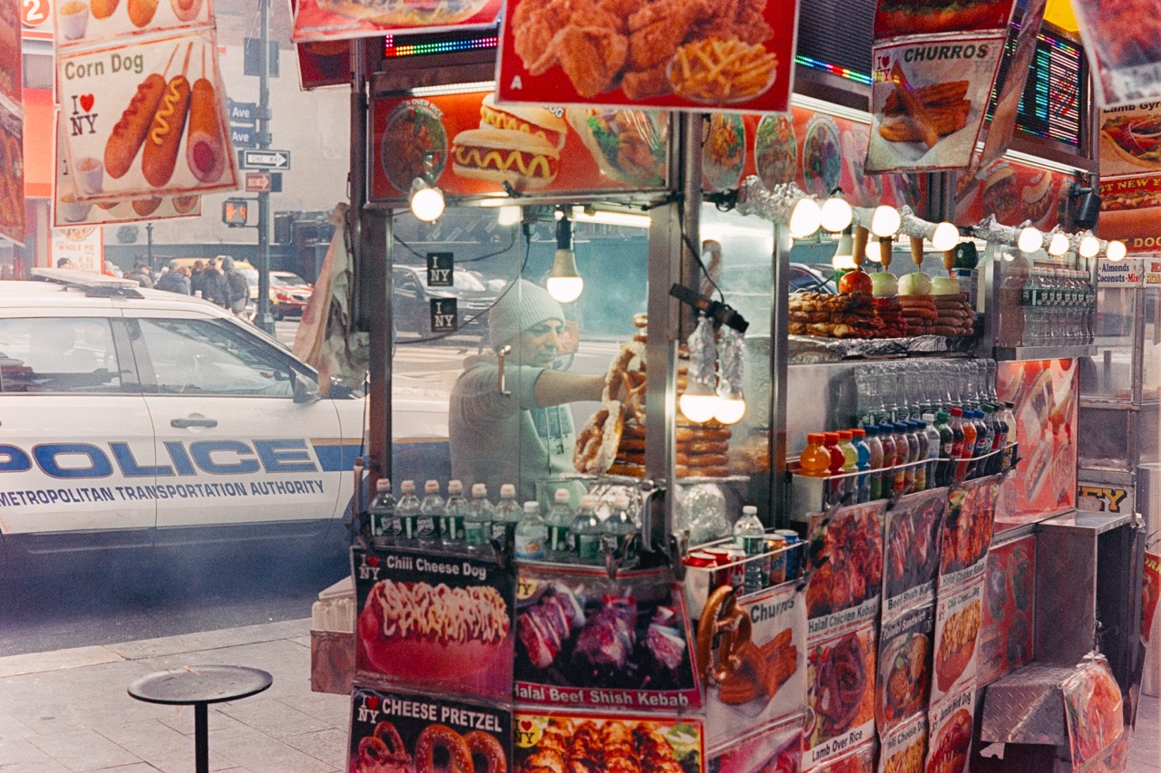 Colorful street food cart with police car in background, Manhattan street scene