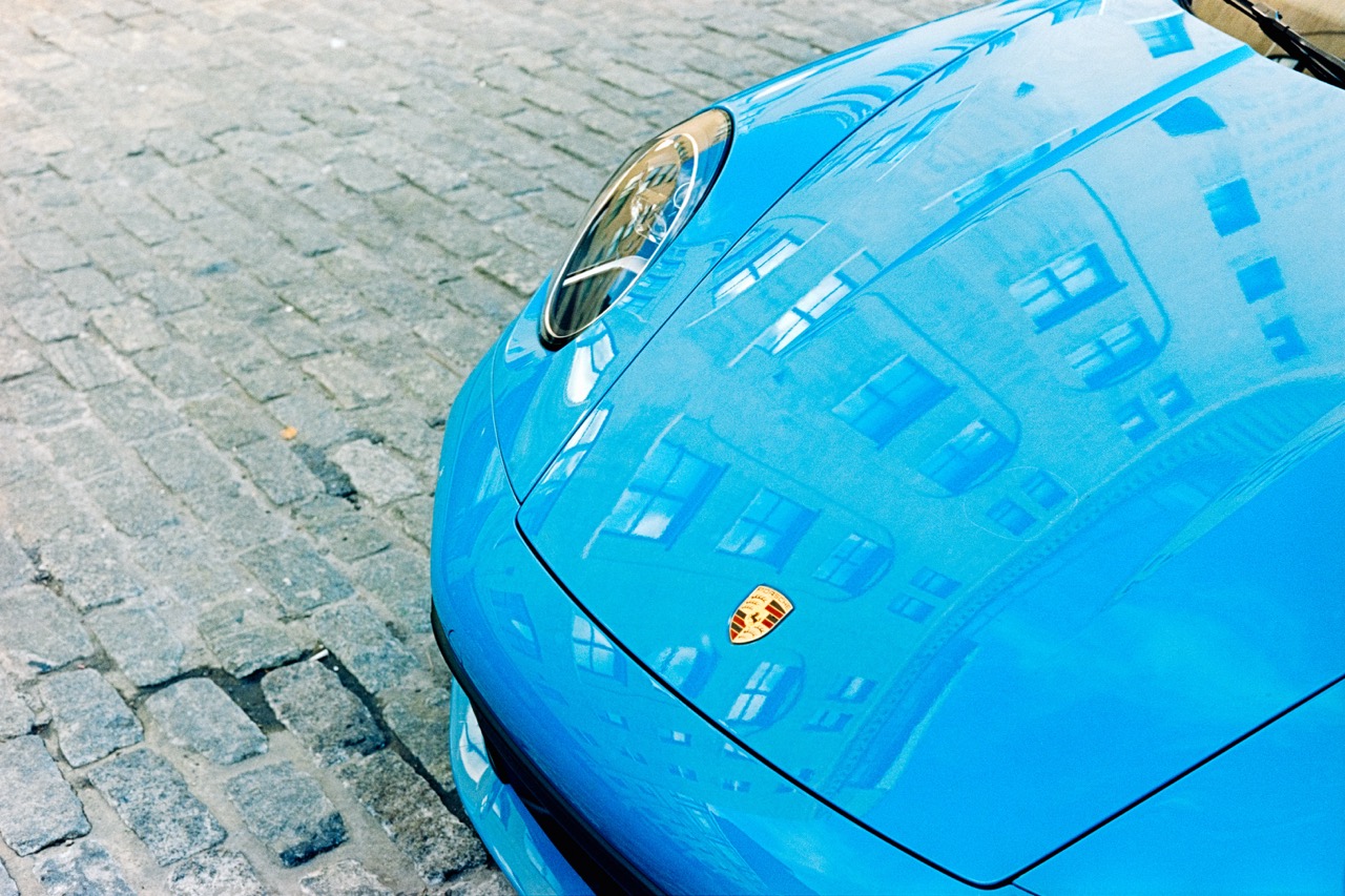 Close-up of blue Ferrari hood on cobblestone street