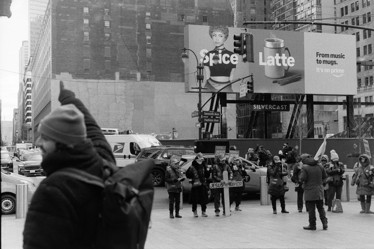 Black and white street scene with coffee shop sign and bundled pedestrians